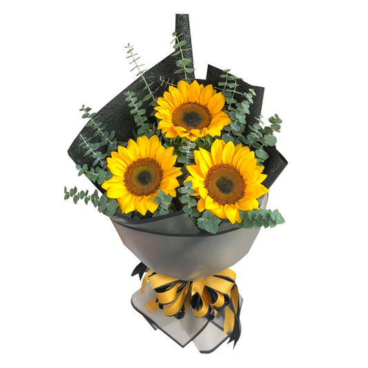 Radiant sunflower trio with Eucalyptus leaves: Korean wrapped bouquet adorned with a border, tissue wrap, and a satin ribbon, exuding natural beauty. Perfect for delivery to Ayala Malls Manila Bay and Robinsons Place Manila.